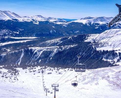 Esquiadores subiendo en el teleférico con montañas cubiertas de nieve y un paisaje invernal en el fondo