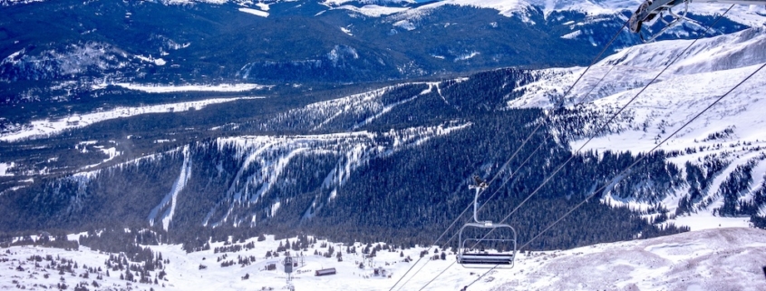 Esquiadores subiendo en el teleférico con montañas cubiertas de nieve y un paisaje invernal en el fondo