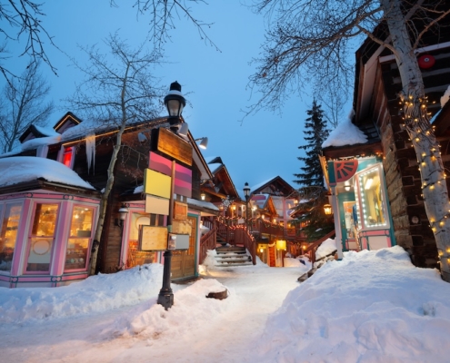 Local businesses with bright lights along a snow-covered street in Breckenridge