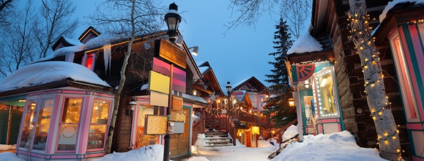 Local businesses with bright lights along a snow-covered street in Breckenridge
