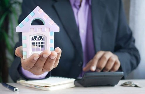 Man holding a toy house at an office desk