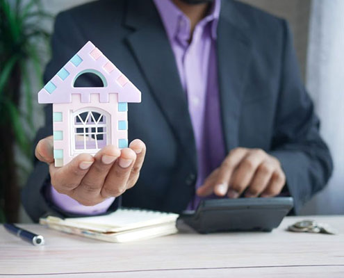 Man holding a toy house at an office desk