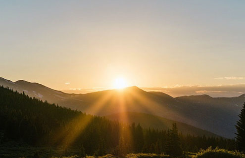 Mountain sunshine rays by setting sun