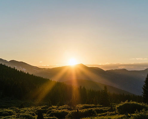 Mountain sunshine rays by setting sun