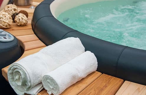 Towels rolled up and sitting next to a hot tub