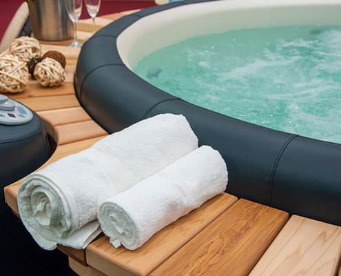 Towels rolled up and sitting next to a hot tub
